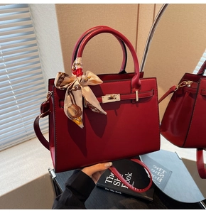 Detail of red bridal handbag with matte leather finish and decorative silk scarf handle