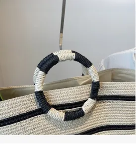 Detail of woven straw tote bag with round handles wrapped in black and white cords