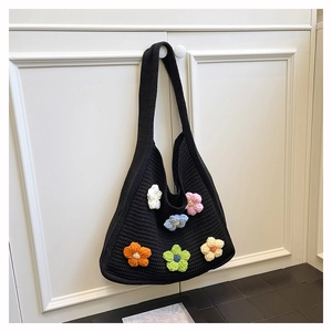 Detail of black knit tote bag featuring colorful 3D crochet flowers and soft texture