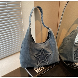 Detailed texture of dark wash denim tote bag featuring an embossed star and wide shoulder strap