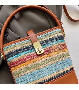 Detail of colorful woven straw bag featuring brown leather trim and golden metal clasp