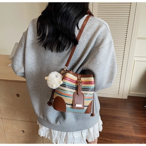 Detail of colorful woven straw bucket bag with brown leather straps and plush lamb charm