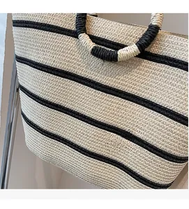 Close-up of woven tote bag featuring black and white stripes and round top handles