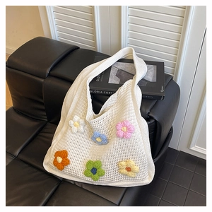 Detailed macro shot of handmade colorful crochet flowers on a beige woven tote bag