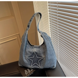 Detail of light blue washed denim tote bag with 3D star embossing and integrated strap