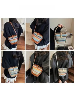 Detail view of multi-color striped straw bucket bag with leather strap and metal buckle