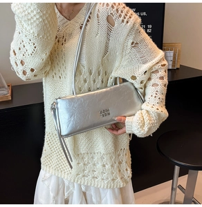 Détail du sac en cuir argenté brillant avec texture froissée et logo estampé
