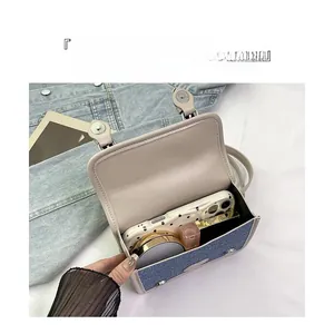 Detail view of denim crossbody bag interior showing storage for phone and lipstick