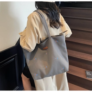 Detail view of charcoal gray canvas tote bag featuring embroidered QZBG lettering