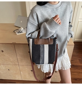 Detail of the woven canvas texture and brown leather trim on a versatile bucket bag