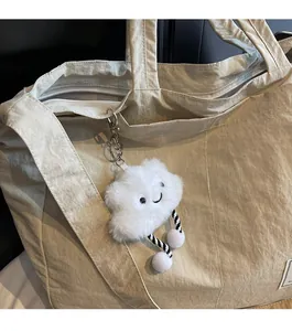 Gros plan d'un charmant pendentif nuage blanc en peluche sur un sac fourre-tout