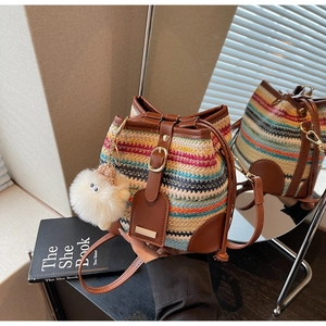 Detail of colorful striped woven bucket bag with brown leather trim and plush charm