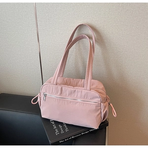 Detailed shot of pink nylon tote bag with silver zipper and drawstring on artistic book