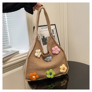 Close-up of handmade knit tote bag featuring colorful 3D crochet flower decorations