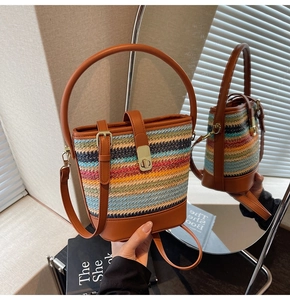 Detail of colorful hand-woven straw bucket bag with brown leather handles and gold clasp
