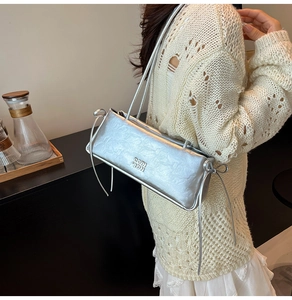 Gros plan du sac à bandoulière rectangulaire argenté avec nœuds et lettres gravées