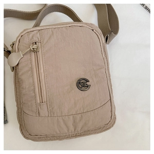 Detailed view of beige nylon crossbody bag with crinkle texture and metal logo