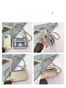 Detail view of denim and faux leather patchwork mini bag with heart logo and gold buckles