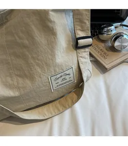 Détail de la bandoulière réglable et du tissu en nylon d'un sac de voyage beige