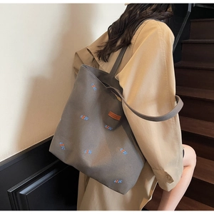 Detailed view of taupe canvas tote bag with blue and orange QZBG letter embroidery