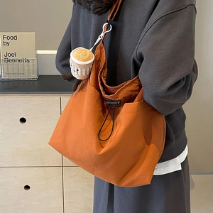 Grand sac cabas orange à cordon avec charm en peluche porté par un mannequin décontracté