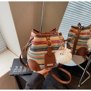 Close-up of colorful woven bucket bag featuring brown leather trim and metal clasp detail