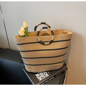 Detail of hand-woven straw tote with black stripes and unique circular braided handles