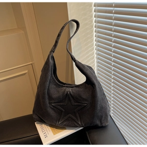 Detail view of the embossed star design on the dark gray washed denim tote bag
