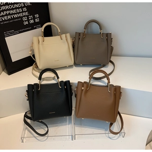 Four colors of textured leather bucket bags with circular metal handles on display