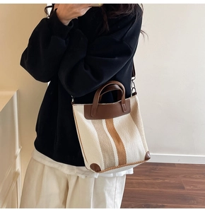 Detail of beige canvas tote with brown leather trim and detachable shoulder strap