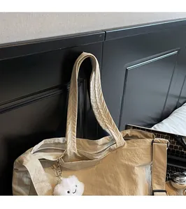 Détail du grand sac de voyage beige avec tissu froissé et breloque nuage mignonne