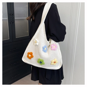 Detail of white crochet tote bag with 3D colorful knit flowers and texture