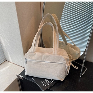 Close-up of minimalist cream canvas tote bag showing pleated nylon texture and zipper pocket