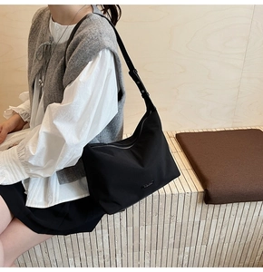 Detail of black nylon hobo bag with adjustable leather strap and metal logo plaque