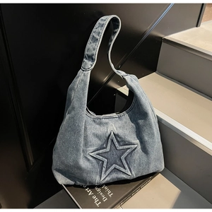 Detail of blue denim tote bag featuring a stitched 3D star and vintage washed finish