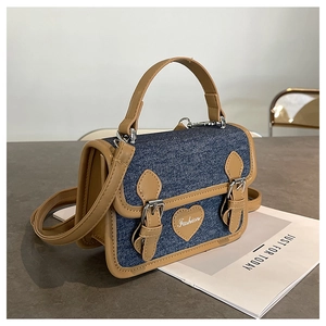 Detailed side view of denim mini crossbody bag with brown leather trim and heart patch