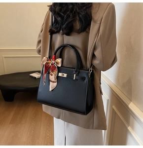 Classic black leather handbag with decorative silk scarf styled on a tan blazer outfit