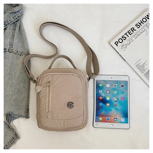 Detail of lightweight beige nylon shoulder bag with vertical zipper and adjustable strap