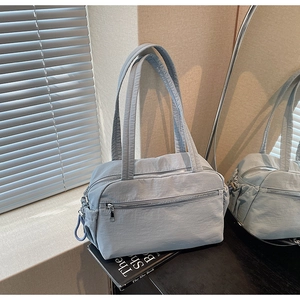 Detail view of light blue nylon tote bag with front zipper pocket and side drawstring