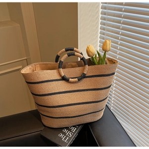 Detail of hand-woven straw tote bag with black stripes and unique dual round handles