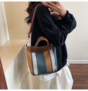 Detail view of a vintage striped woven bucket bag with leather handles and adjustable strap