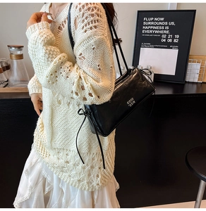 Vue latérale d'un sac à bandoulière en cuir noir avec lettrage métallique COIN IDN
