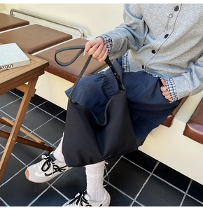 Minimalist black tote bag with leather straps styled in a casual outdoor lifestyle scene