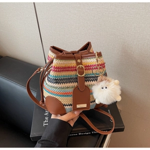 Detail of colorful woven straw bucket bag with leather strap and cute sheep charm pendant