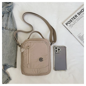 Detail of beige nylon crossbody bag showing zip compartment and smartphone size comparison