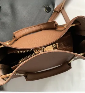 Detail of smooth metal zipper and brown litchi grain leather on a bucket bag