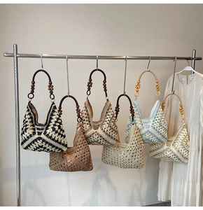 Various hand-woven tote bags with beaded wooden handles displayed on a minimal wall