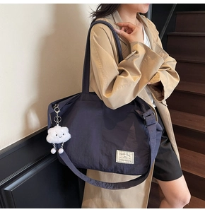 Vue détaillée du sac de voyage en nylon bleu marine avec breloque nuage et bandoulière