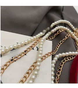 Detailed close-up of premium cream white pearls and polished gold metal chain accessory