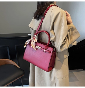 Detail of red leather bridal handbag with metal twist lock and decorative scarf accessory